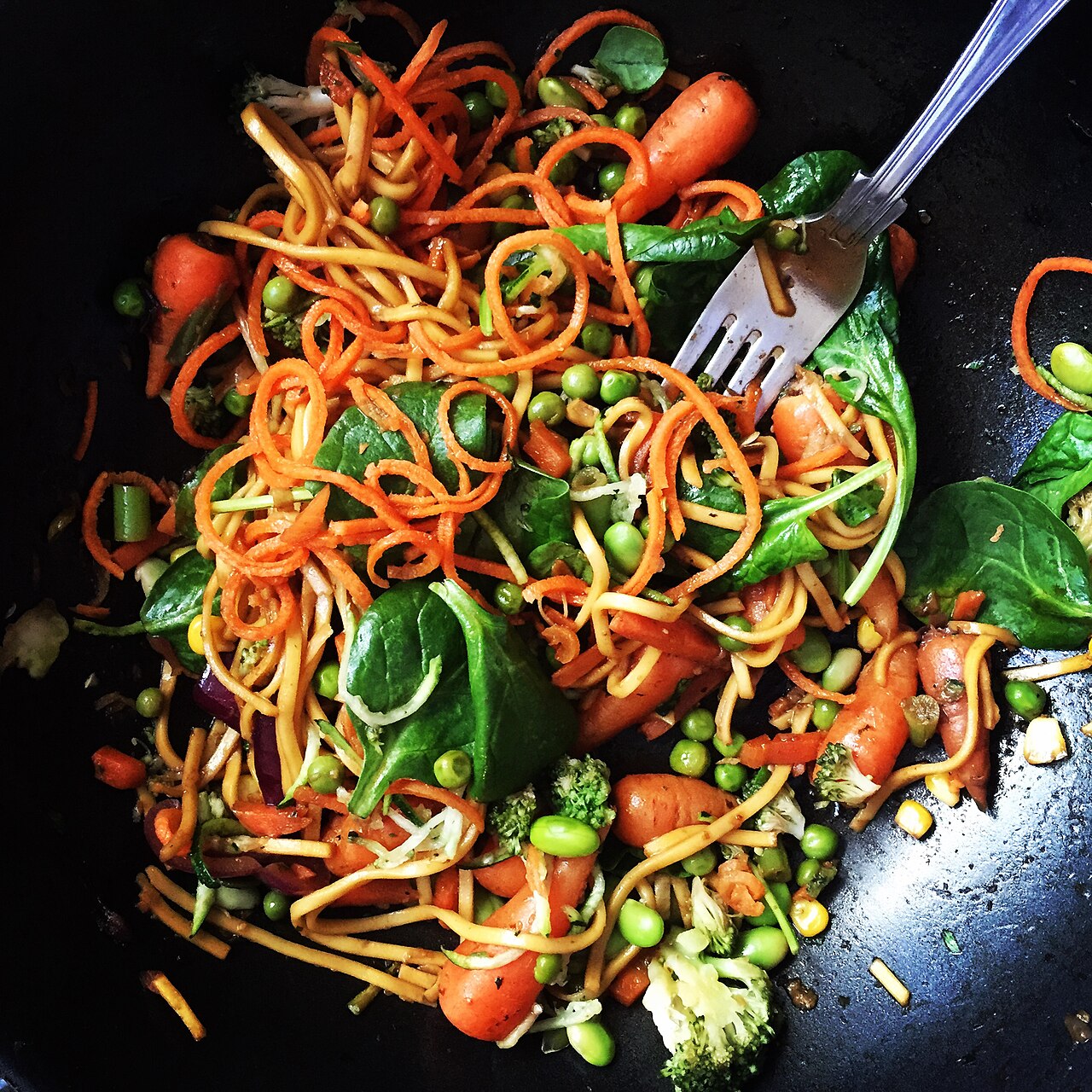 Fresh vegetables being stir-fried in a wok over a kitchen stove
